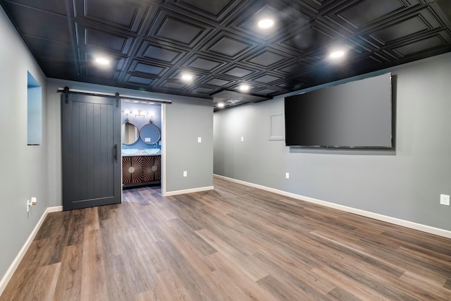 cinema room featuring an ornate ceiling, wood finished floors, baseboards, and a barn door