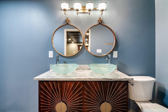 bathroom with a sink, toilet, and double vanity