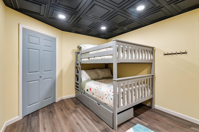 bedroom with recessed lighting, wood finished floors, an ornate ceiling, and baseboards