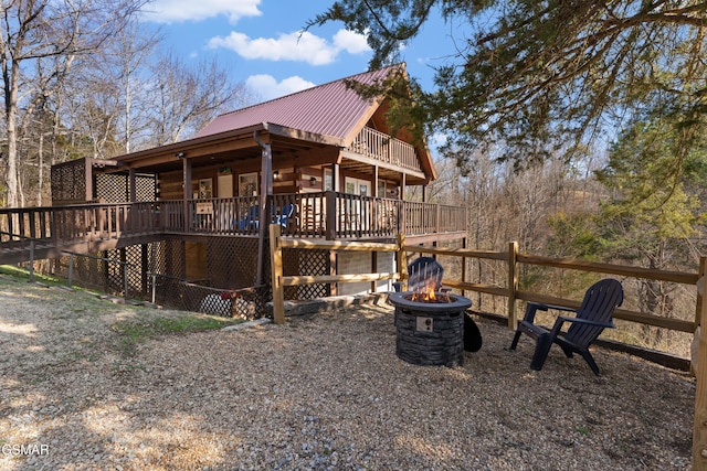 view of property exterior with log exterior, metal roof, a fire pit, and a wooden deck