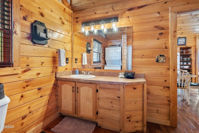 3290 Emerald Springs Loop, Sevierville, TN 37862 - bathroom with vanity, stacked washer and dryer, wooden walls, and wood-type flooring