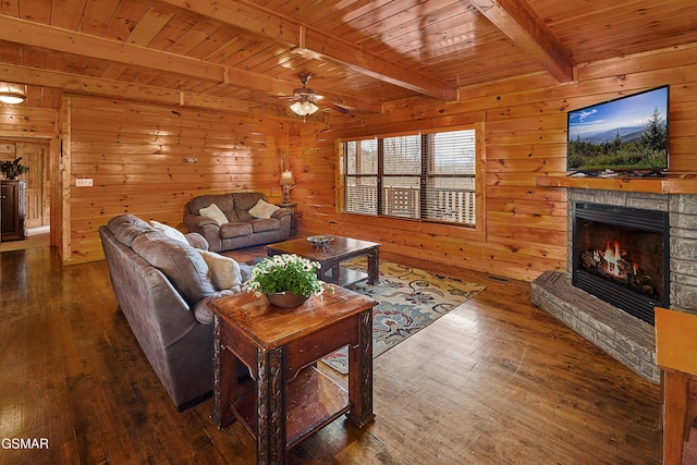 living room featuring hardwood / wood-style floors, beamed ceiling, a stone fireplace, ceiling fan, and wood ceiling