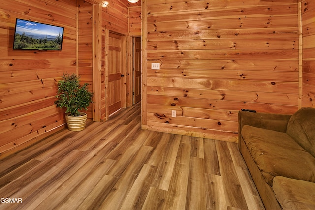 unfurnished room with wood walls and light wood finished floors
