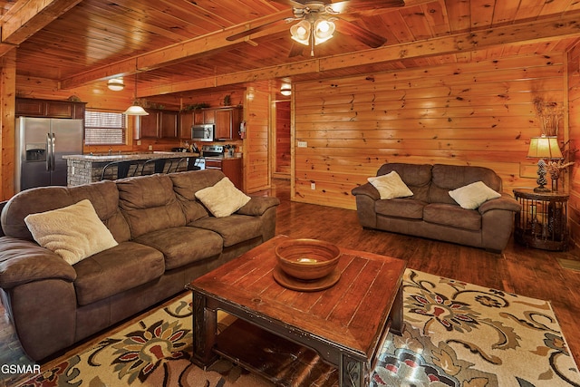 living room featuring wood ceiling, a ceiling fan, dark wood finished floors, beam ceiling, and wooden walls