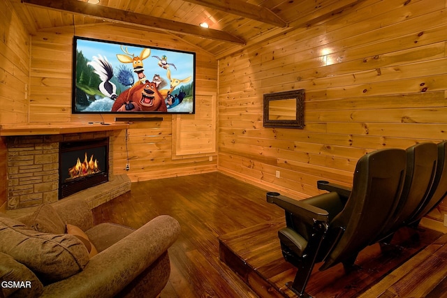cinema room with wooden walls, a stone fireplace, wood ceiling, and dark wood-type flooring