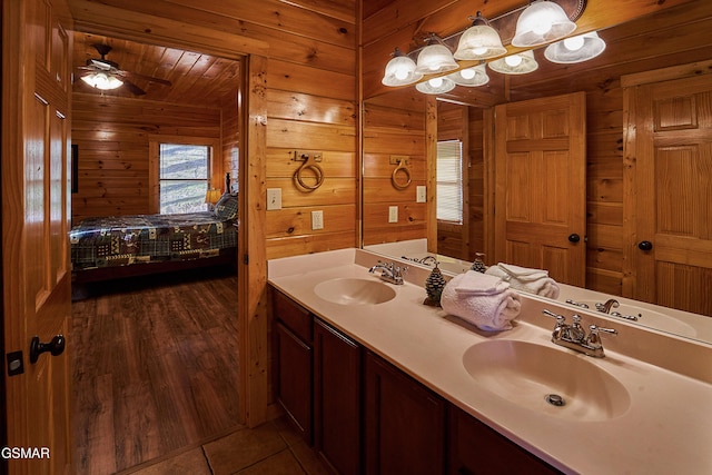 ensuite bathroom featuring connected bathroom, double vanity, wood walls, and a sink