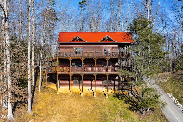 view of front of house featuring faux log siding, a deck, and metal roof