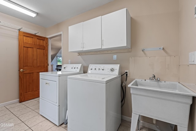 laundry room with a sink, washing machine and dryer, light tile patterned flooring, baseboards, and cabinet space