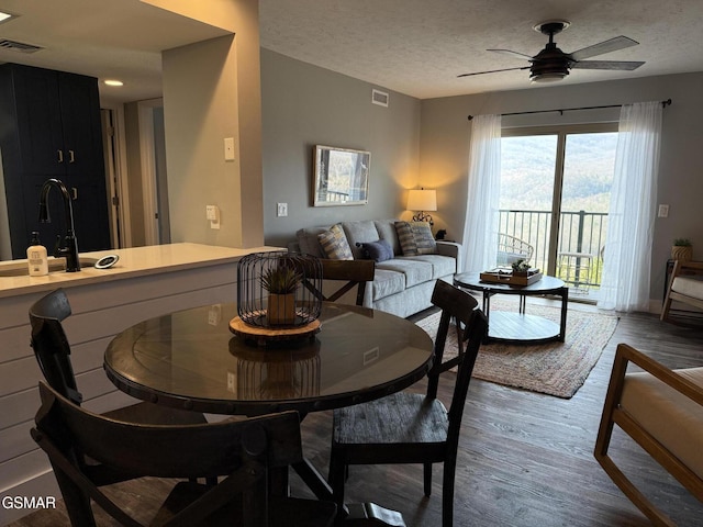 dining room featuring wood finished floors, a textured ceiling, ceiling fan, and visible vents
