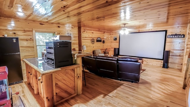 home theater room with light hardwood / wood-style flooring, wood walls, and wood ceiling