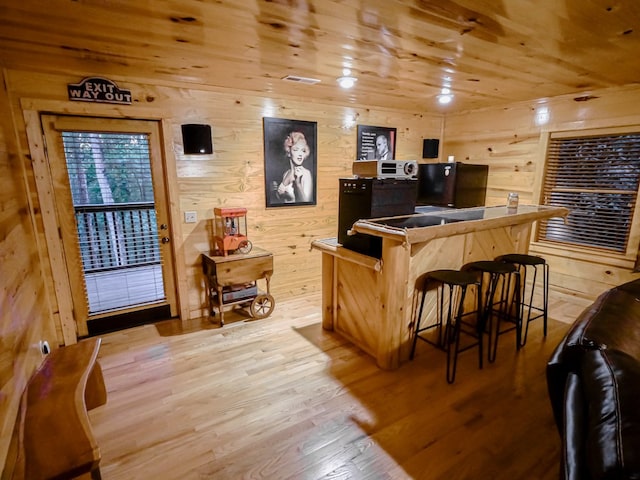 bar with light hardwood / wood-style floors, wood walls, and wooden ceiling