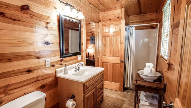 bathroom with wooden ceiling, tile patterned floors, wood walls, toilet, and vanity