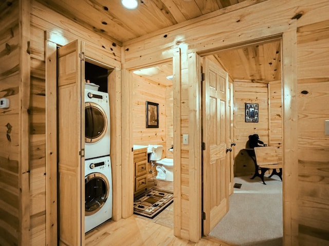 laundry room featuring wood walls, stacked washer and dryer, and wooden ceiling