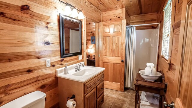 bathroom featuring vanity, wood walls, wooden ceiling, tile patterned flooring, and toilet