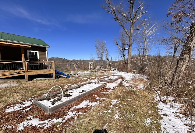 yard layered in snow featuring a playground and a deck