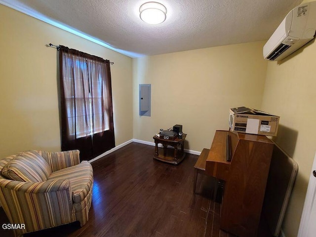 sitting room featuring a textured ceiling, dark wood-type flooring, baseboards, a wall mounted AC, and electric panel