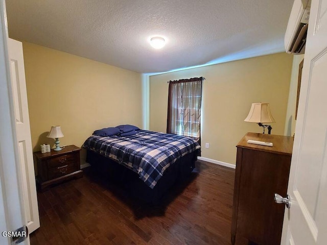 bedroom with dark wood-style floors, a textured ceiling, a wall mounted air conditioner, and baseboards