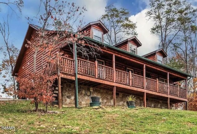 back of house featuring a yard, log siding, a wooden deck, and stone siding