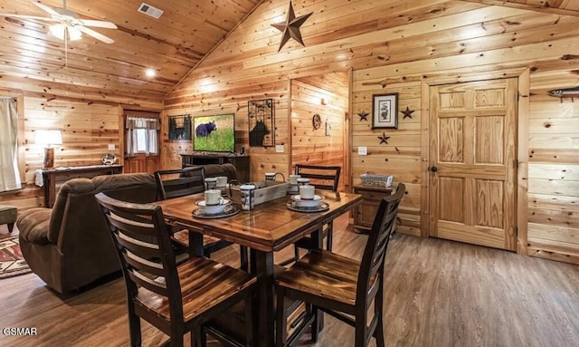 dining area featuring wood ceiling, ceiling fan, visible vents, wood walls, and wood finished floors