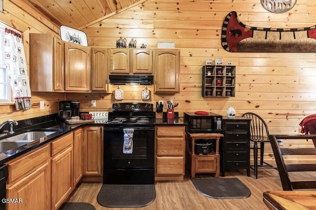 kitchen with wood walls, light wood-style flooring, exhaust hood, and black appliances