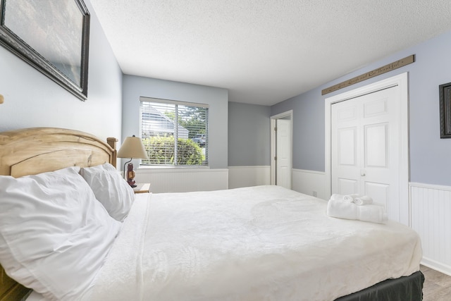 bedroom featuring wood-type flooring, a textured ceiling, and a closet