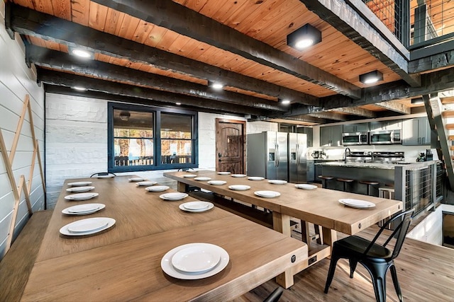 dining area with french doors, sink, light hardwood / wood-style flooring, beamed ceiling, and wood walls