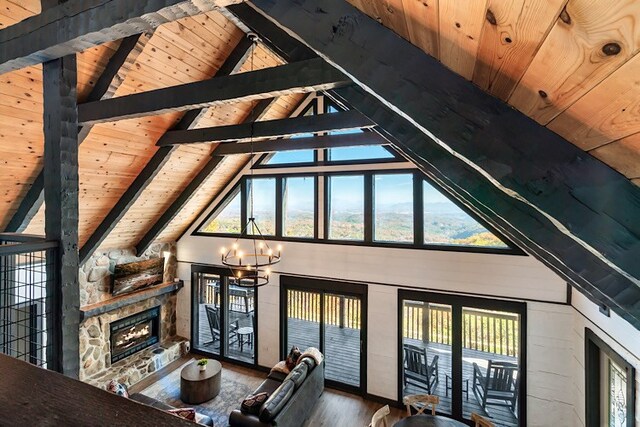 unfurnished living room with wooden ceiling, a notable chandelier, beamed ceiling, hardwood / wood-style floors, and a stone fireplace