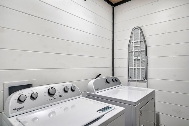 washroom featuring washer and dryer and wooden walls