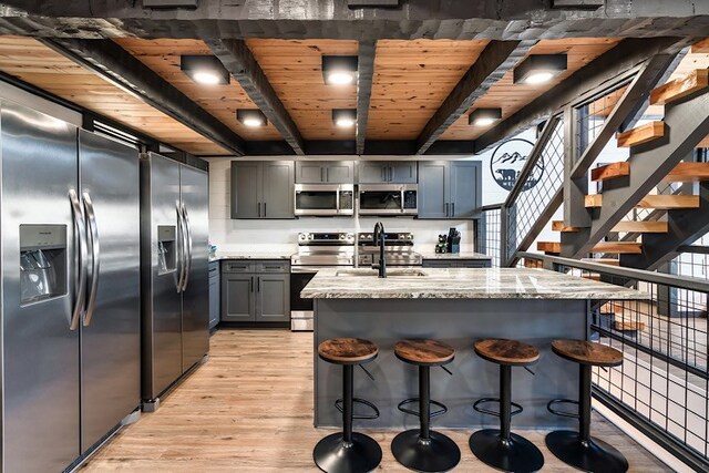 kitchen featuring sink, light hardwood / wood-style flooring, appliances with stainless steel finishes, beamed ceiling, and wood ceiling