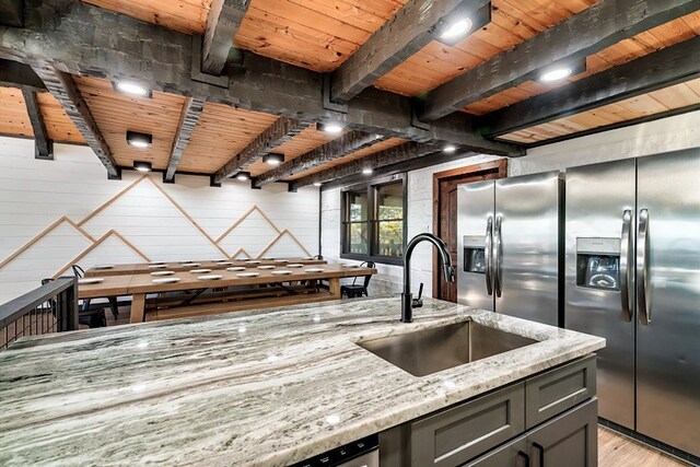 kitchen with sink, gray cabinets, beamed ceiling, light hardwood / wood-style floors, and light stone counters