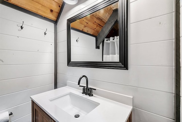 bathroom with vanity, vaulted ceiling, wooden ceiling, and wood walls