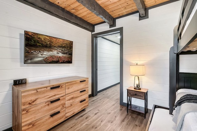 bedroom featuring beam ceiling, wood walls, light hardwood / wood-style flooring, and wooden ceiling