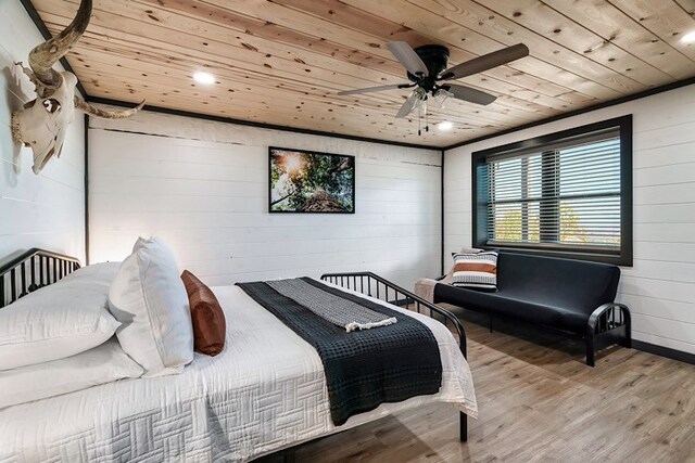 bedroom with ceiling fan, wooden walls, wood ceiling, and light wood-type flooring