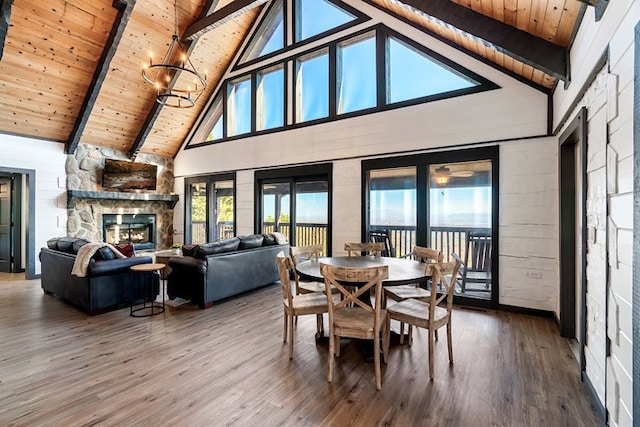 dining room featuring wooden ceiling, a stone fireplace, high vaulted ceiling, beamed ceiling, and hardwood / wood-style flooring