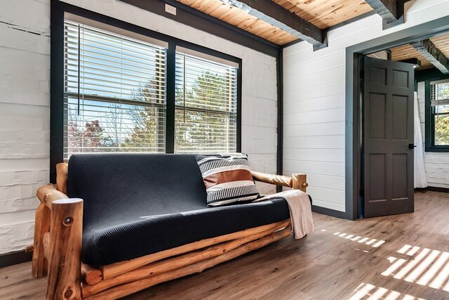 living area featuring beamed ceiling, hardwood / wood-style flooring, wooden ceiling, and wood walls