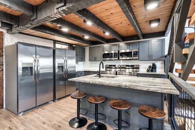 kitchen with wood ceiling, stainless steel appliances, sink, beam ceiling, and light hardwood / wood-style floors