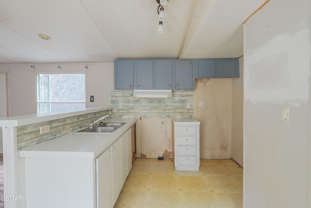 kitchen featuring a peninsula, light countertops, light floors, and a sink