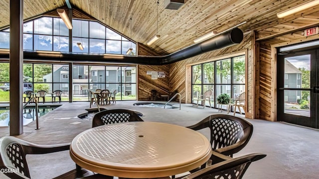 dining space featuring high vaulted ceiling, a healthy amount of sunlight, wood ceiling, and wooden walls