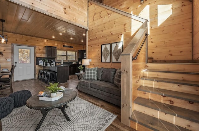 living area featuring stairs, dark wood-type flooring, wood ceiling, and wood walls