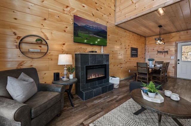 living room with wooden ceiling, wooden walls, wood finished floors, and a tile fireplace