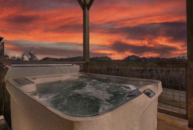 pool at dusk with a hot tub