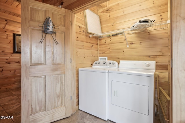 laundry area with wood walls and washing machine and clothes dryer