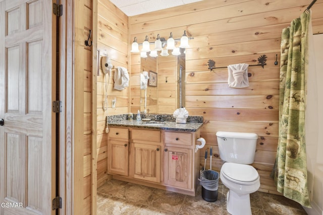 bathroom featuring curtained shower, wooden walls, toilet, and vanity