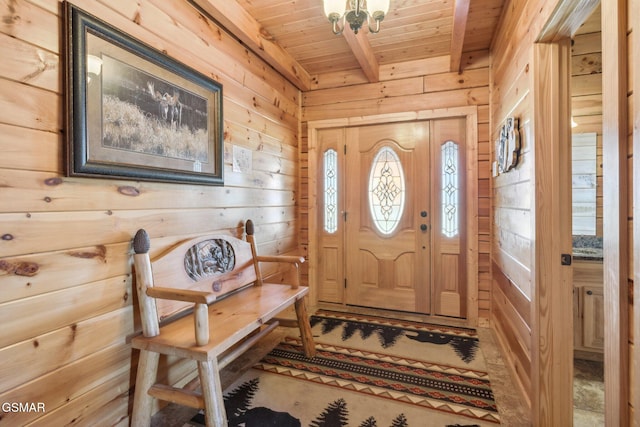 foyer entrance with an inviting chandelier, wood ceiling, wooden walls, and beam ceiling