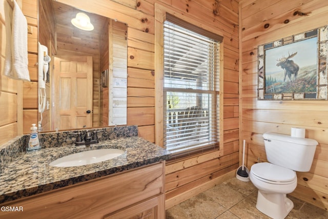 bathroom featuring vanity, toilet, and wooden walls