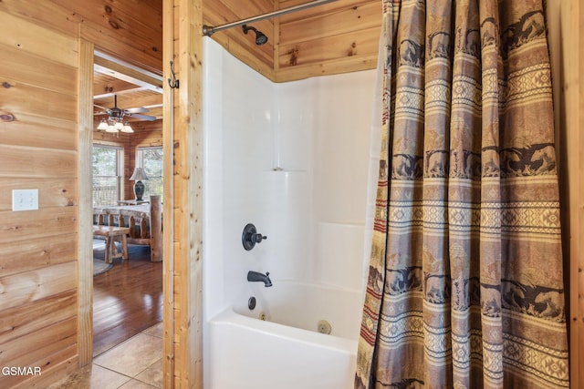 full bath with tile patterned flooring, ceiling fan, wooden walls, and shower / bath combo with shower curtain