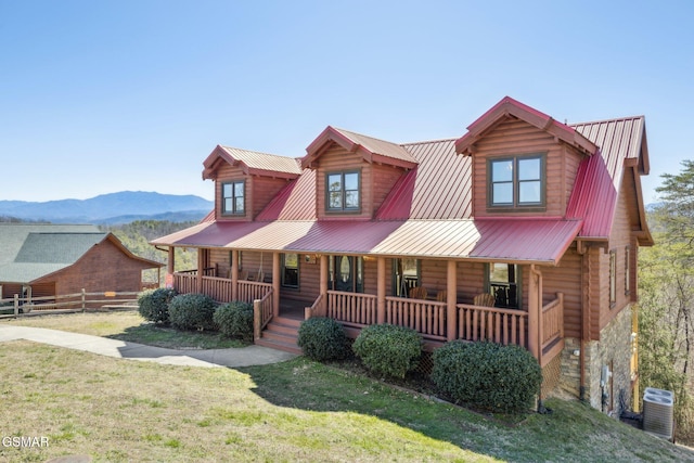 view of front of house with covered porch, metal roof, a front yard, and a mountain view