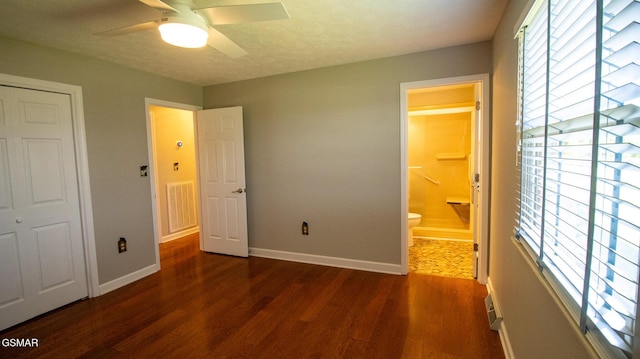 unfurnished bedroom with baseboards, connected bathroom, visible vents, and wood finished floors