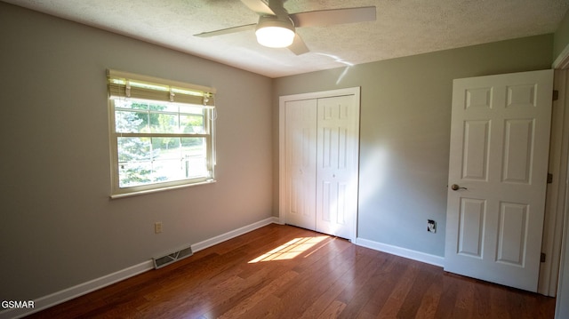 unfurnished bedroom featuring a closet, wood finished floors, a textured ceiling, visible vents, and baseboards