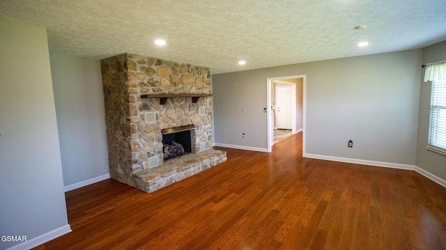unfurnished living room with recessed lighting, a textured ceiling, baseboards, wood finished floors, and a fireplace